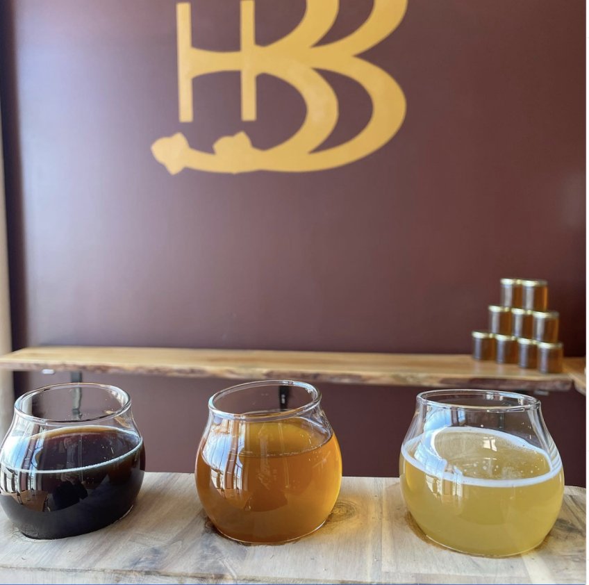 a flight of braggot at Braggot Brewing with a large logo on the tasting room wall