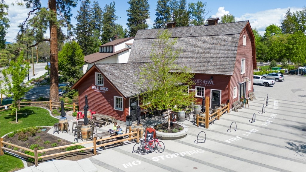 a drone photo of Barn Owl Brewing and Milk Shed coffee with their outdoor patios and bike racks in Kelowna